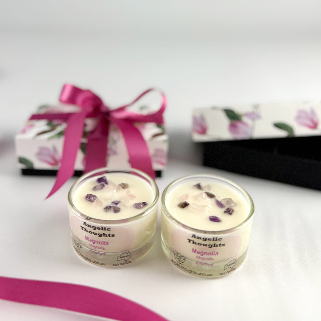 magnolia scented rose quartz and amethyst embellished hand poured tealights in glass tealight containers with magnolia 2pack tealight product box tied with deep pink ribbon in background