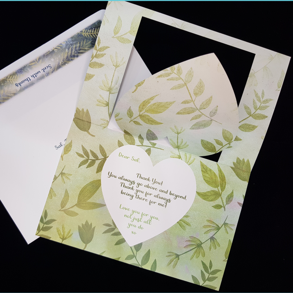 An open card lays on a matching envelope. The entire inside of the card background consists of green foliage.  A white heart slightly smaller that the cutout heart sits centrally overlaid on green foliage. A thank you message is written in a light green with the verse in a darker green. Fully customisable