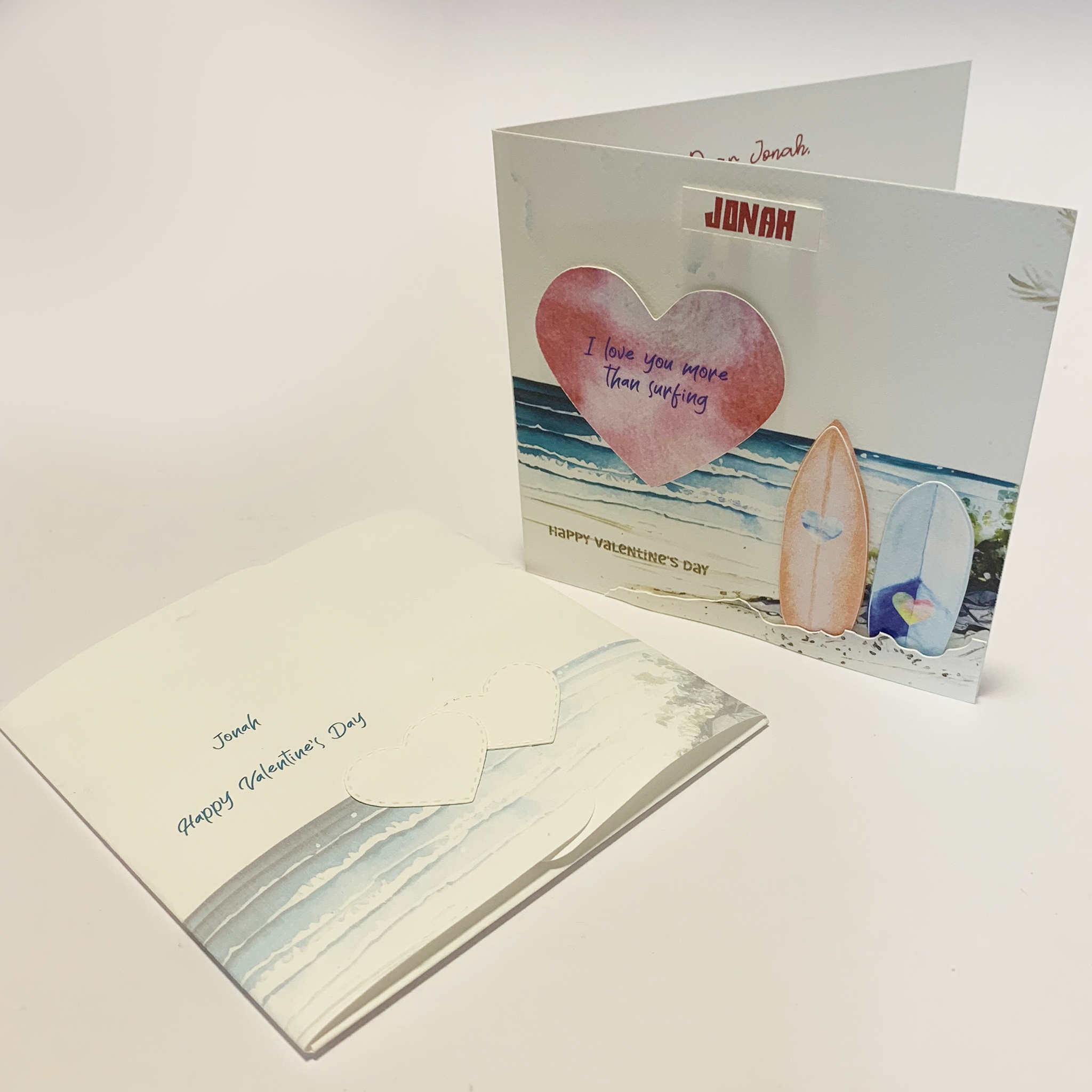 photo of Valentines Personalized Romantic Ocean Greeting Card with Surfboards standing upright and custom personalised folder laying down in front